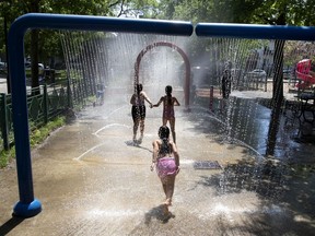 Kids run through the splash pad installations at Parc de Lestre during early heat wave in Montreal on Wednesday, May 27, 2020.