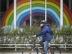 Cyclist wearing mask rolls by rainbow on Sherbrooke on Tuesday May 5, 2020. (Pierre Obendrauf / MONTREAL GAZETTE) ORG XMIT: 64307 - 4718