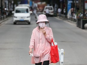 A woman wears a face shield as she walks along a street in Wuhan in China's central Hubei province on May 11, 2020.