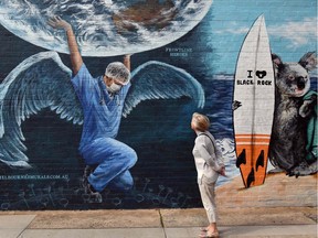 A woman looks at a mural of a health worker with wings holding a globe on International Nurses Day in Melbourne on May 12, 2020.
