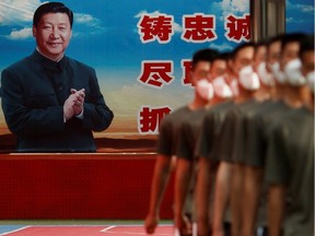 Paramilitary Police officers march in formation near a poster of Chinese President Xi Jinping at the gate to the Forbidden City on Friday, the opening day of the National People's Congress (NPC) following the outbreak of the coronavirus disease (COVID-19).