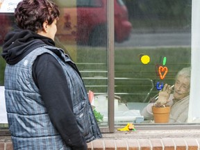 Annette Demeny, left, visits through the window with her friend Concetta Lamberto at the Vigi Mount Royal seniors residence on Friday, May 1, 2020, in Montreal North. The area has been identified as one of the hardest hit with COVID-19 on the island.