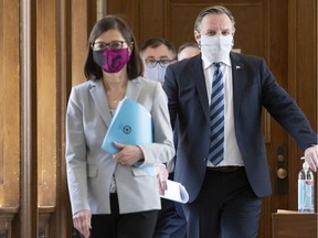 Health Minister Danielle McCann, left, Quebec Premier François Legault, right, and Horacio Arruda, Quebec director of public health, behind, walk to a news conference on the COVID-19 pandemic wearing masks, Tuesday, May 12, 2020 at the legislature in Quebec City.