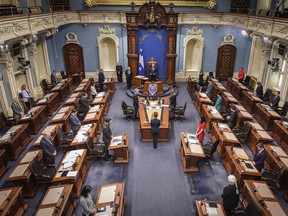 Members of the National Assembly stand in a minute of silence to honour victims as the legislature resumes with limited attendance of members during the COVID-19 pandemic, Wednesday, May 13, 2020 at the legislature in Quebec City.