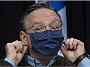 Quebec Premier François Legault pulls off his face mask at the beginning of a news conference on the COVID-19 pandemic, Monday, May 18, 2020 at the legislature in Quebec City.
