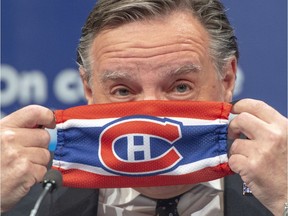 Quebec Premier François Legault puts on a Canadiens mask as he finishes the daily COVID-19 news briefing in Montreal on May 21, 2020.