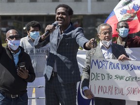 Wilner Cayo, centre, and Frantz Andre attend a demonstration outside Prime Minister Justin Trudeau's constituency office in Montreal, Saturday, May 23, 2020, where they called on the government to give residency status to migrant workers as the COVID-19 pandemic continues in Canada and around the world.