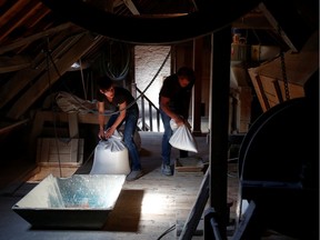 Miller Adrienne Delacroix and a baker carry bags of spelt grains at the Hollange watermill during the coronavirus disease (COVID-19) outbreak in Fauvillers, Belgium, on Wednesday, May 20, 2020.