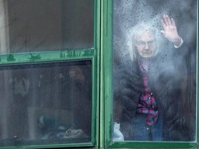 A resident waves from her window at Residence Herron, a senior's long-term care facility in the suburb of Dorval in Montreal. The virus swept through that long-term care home, exposing horrible conditions for many seniors.