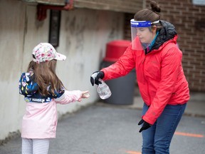 A student has her hands sanitized in the schoolyard, as schools outside Greater Montreal began to reopen their doors on May 11, 2020.