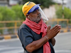 A man wearing a protective face shield prays outside a temple during an extended lockdown to slow the spreading of the coronavirus disease (COVID-19), in Ahmedabad, India, on Sunday, May 10, 2020.