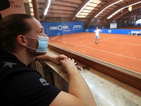 Jean-Marc Werner, a German tennis player of the ATP world tour, wears a face mask as he watches his country fellow Johannes Haerteis playing in an exhibition tennis match, without spectators, and broadcasted by remote controlled cameras, during the spread of the coronavirus disease (COVID-19) in a tennis academy in Hoehr-Grenzhausen, near Koblenz, Germany, May 2, 2020.