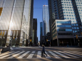 A woman crosses the street during morning commuting hours in the Financial District in Toronto.