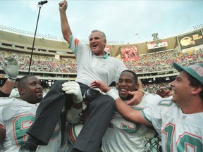 Miami Dolphins coach Don Shula is carried off the field by players Keith Sims (L) and Larry Webster (C) after Miami defeated Philadelphia 19-14 in Philadelphia November 14, 1993. This win made Shula the most successful coach in the league, giving him his 325th career victory.