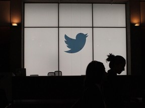 In this file photograph taken on August 14, 2019, employees walk past an illuminated Twitter logo as they leave the company's headquarters in San Francisco.