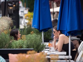 Two women have drinks on the patio at an Earls restaurant, in Vancouver, on Tuesday, May 19, 2020. British Columbia began phase two of the reopening of its economy Tuesday, allowing certain businesses that were ordered closed due to COVID-19 to open their doors to customers if new health and safety regulations are followed.