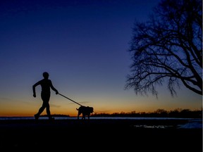 A woman runs with her dog at sunset on the waterfront in the Lachine borough of Montreal Sunday March 15, 2020.