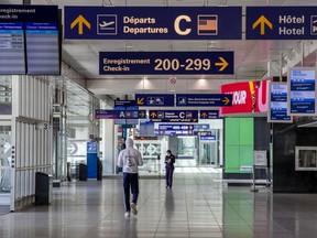 A couple of people walk through empty Montréal-Pierre Elliott International Airport in Montreal Thursday May 7, 2020. (John Mahoney / MONTREAL GAZETTE) ORG XMIT: 64368 - 3552
