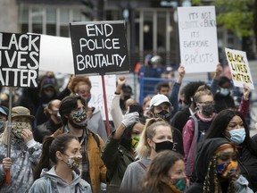 Protesters hold up signs during anti-racist and anti-police brutality demonstration on Sunday May 31, 2020. Most protesters are wearing mask for the COVID-19 pandemic (Pierre Obendrauf / MONTREAL GAZETTE)