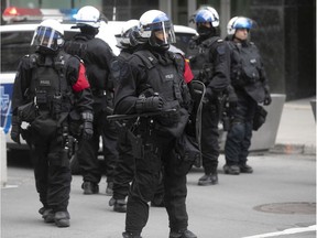 Members of the Montreal riot squad stand on the corner of Ste-Catherine and Stanley Sts. during Sunday's anti-racism and anti-police brutality demonstration.