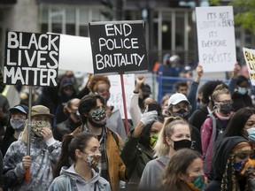 Protesters hold up signs during protest against racism and police brutality in Montreal on May 31, 2020.