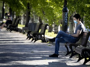 A man reads his phone away from others at Champ de Mars park in late May. The hardest-hit age group in Montreal continues to be people 80 and older, followed by those in their 40s.