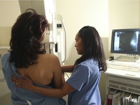 A technician aids a patient during a mammogram.