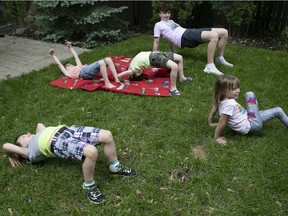 Counsellor Zev Wood, seen in background, leads kids in yoga exercises during a backyard summer camp program in Montreal West organized by Learn 'N Play on Wednesday June 10, 2020. Note social distancing being practised as well as five-year-olds can practise it: Benjamin MacMahon, front left, Megan Copeland, right, and, on red mat, twins Tobin and Rory Coughlin.