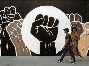 A coalition of artists came together to produce this mural on the boarded-up Apple Store on Ste-Catherine St. in Montreal. Lion Harris and Sandrine Laurier walk past the mural in June 2020.
