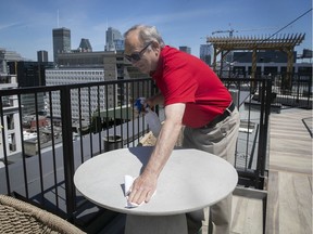 Jeffrey Boro, president of the board of directors of the Linton condo building, cleans tables on the rooftop terrace on Wednesday. The building's gym and rooftop terrace have stayed open during the pandemic.
