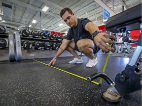 Alex Franco, head personal trainer at Club Fit Forme on Montreal's West Island, uses a tape measure to space out equipment on Wednesday in order to get the gym ready for its reopening on Monday.