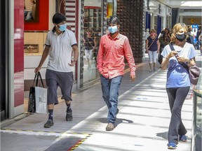 Shoppers wear masks as they walk through the Fairview Pointe-Claire mall on June 19, 2020.