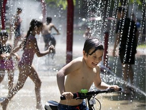 Nathaniel Verzamanis rides his bike through the splash pad installations at Parc De Lestre in May. Kids have to practise patience at splash pads and pools this summer, Allison Hanes writes. Social-distancing measures still apply, meaning long lineups to swim or run through the waterworks.