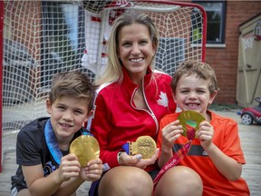Kim St-Pierre and her boys Liam, left, and Ayden hold her three Olympic gold medals at her home in the St-Laurent borough of Montreal on June 26, 2020. St-Pierre was elected to the Hockey Hall of Fame this week.