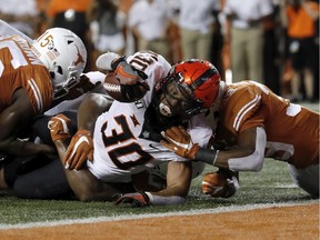 Chuba Hubbard #30 of the Oklahoma State Cowboys is stopped short of the goal line by Chris Brown #15 of the Texas Longhorns and Montrell Estell #39 in the second quarter at Darrell K Royal-Texas Memorial Stadium on September 21, 2019 in Austin, Texas.