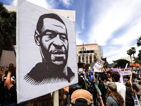 A protester holds a sign with an image of George Floyd during a peaceful demonstration over Floyd's death outside LAPD headquarters on June 2, 2020, in Los Angeles.
