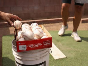 Baseballs are taken from a box as MLB pitchers practice in a backyard throwing session on June 05, 2020 in Scottsdale, Arizona.  Since the MLB season was paused indefinitely due to the coronavirus COVID-19 pandemic, players have been using the back yard at Seth Blairs' house to train and work on mechanics.