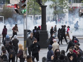 Protesters run from police during a demonstration calling for justice in the death of George Floyd and victims of police brutality in Montreal, Sunday, May 31, 2020.