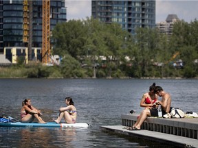 Anne-Sophie, left, and Maryse, relax on their paddle board as Maxime Dursin and Nadia Saadoune sit on a wharf on the St. Lawrence River during a heat wave in Montreal, on Monday, June 22, 2020.