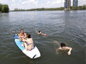 Anne-Sophie, left, and Maryse, relax on their paddle board as a group of boys throw the football around in the water during a heat wave in the Verdun district of Montreal, on Monday, June 22, 2020. (Allen McInnis / MONTREAL GAZETTE)