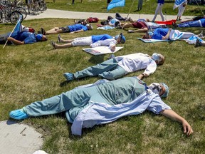 Saying they're "dead from fatigue," health care workers hold a die-in during demonstration outside Maisonneuve-Rosemont Hospital in Montreal Wednesday May 27, 2020.