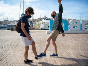 A man and a woman pose as they greet each other with their feet in the Vieux Port of Marseille southern France, on May 17, 2020, in order to use new social distanciation gesture to salute people as a prophylactic measure against the spread of the Covid-19 disease caused by the novel coronavirus.