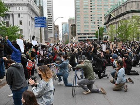 Members of the crowd kneel as a minute of silence is observed in memory of George Floyd during a rally in Montreal May 31, 2020. Floyd was killed by police in Minneapolis.