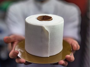 This picture taken on June 4, 2020 shows pastry chef Gabriel Pang Yue Ken, 26, holding a cake designed to resemble a roll of toilet paper at the Le Pont Boulangerie cafe in Kuala Lumpur. - Panic buying around the world due to the COVID-19 novel coronavirus pandemic in recent months saw supermarket shelves emptied of toilet paper rolls, leading the cafe in Kuala Lumpur to craft their cakes after the tissue sheets. (Photo by Mohd RASFAN / AFP)
