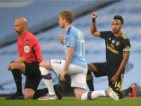 Arsenal's Gabonese striker Pierre-Emerick Aubameyang (R) takes a knee alongside Manchester City's Belgian midfielder Kevin De Bruyne (C) and Referee Anthony Taylor (L) ahead of the English Premier League football match between Manchester City and Arsenal at the Etihad Stadium in Manchester, north west England, on June 17, 2020. - The Premier League makes its eagerly anticipated return today after 100 days in lockdown but behind closed doors due to coronavirus restrictions.