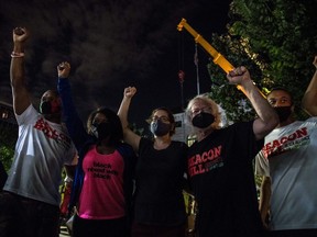 Members of Beacon Hill Black Alliance for Human Rights raise their hands and celebrate as crew members remove the the 30-foot Confederate monument which is been brought down on June 19, 2020, in Decatur northeast of Atlanta, Georgia.