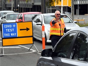 A traffic controller manages cars queueing at a drive-through COVID-19 testing site located in a shopping centre carpark in Melbourne on June 23, 2020. - Australians were warned June 22 to avoid travelling to Melbourne, as the country's second biggest city tightened coronavirus restrictions amid fears of a second wave of the epidemic. (Photo by William WEST / AFP)