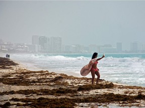 A woman takes a selfie with a cloud of Saharan dust in the background in Cancun, Quintana Roo state, Mexico, on June 25, 2020. A massive cloud of Saharan dust invaded Cancun beaches Thursday and began to affect air quality in Florida, sparking warnings to people with respiratory illnesses to stay home.