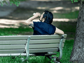 A man sips his beer while sitting in a Toronto park.
