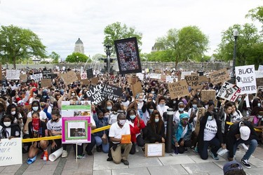 Demonstrators take a knee in memory of George Floyd at a demonstration to denounce police violence, Sunday, June 7, 2020 in front of the legislature in Quebec City. A few thousand people peacefully gathered.